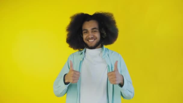 Afro americano uomo sorridente, mentre dando pollici su su sfondo giallo. Concetto di emozioni — Video Stock