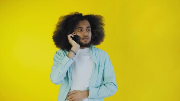 Afro-americano uomo parlando su cellulare mentre in piedi isolato su sfondo giallo — Video Stock