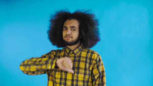 Afro-amerikansk man Gesturing tummar ner på blå bakgrund — Stockvideo