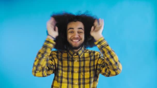 Bezorgd Afro-Amerikaanse man lacht, houdt handen op haar gezicht en viert succes op blauwe achtergrond. — Stockvideo