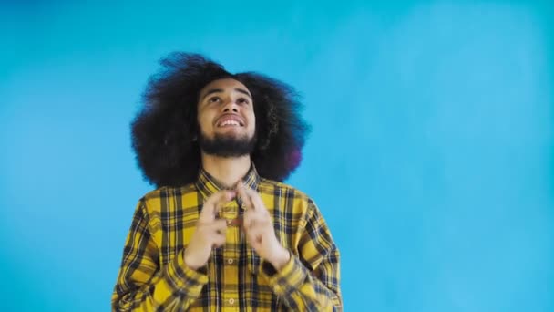 Retrato de un chico afroamericano rezando manteniendo los dedos cruzados y gritando dios por favor sobre fondo azul. Concepto de emociones — Vídeo de stock