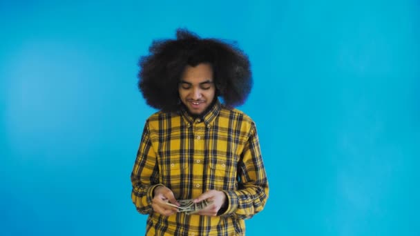 若いアフリカ系アメリカ人男性カウント現金お金上の青の背景. — ストック動画