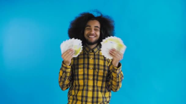 Young African American man holding cash money on Blue background. — Stock Video