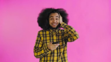 Genç mutlu Afrikalı iş adamı telefonu kullanıyor ve mor arka planda iyi haberler alıyor. Duyguların kavramı