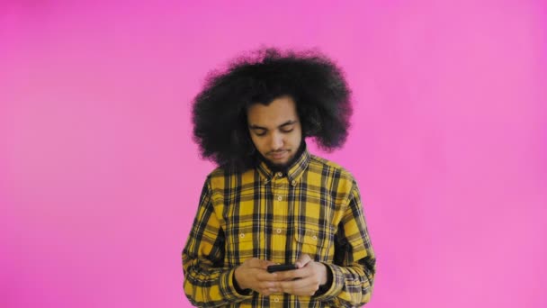 Giovane bell'uomo afroamericano che usa il telefono su sfondo viola. Concetto di emozioni — Video Stock