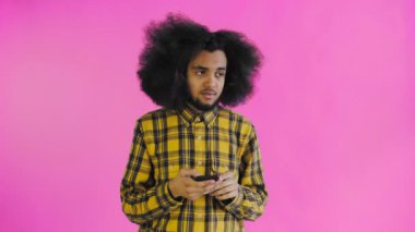 Kıvırcık saçlı Afro-Amerikalı adam mor arka planda mesaj göndermeden önce düşünüyor. Duyguların kavramı