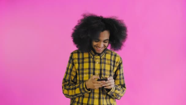 Ritratto di uomo afroamericano con capelli ricci che chatta su smartphone su sfondo viola. Concetto di emozioni — Video Stock