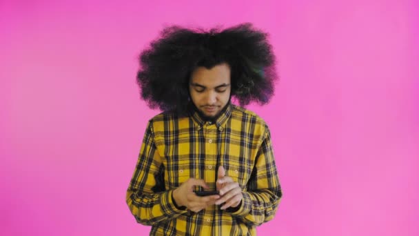 Sfrustrowany młody Afroamerykanin trzymający zepsuty telefon na fioletowym tle. Pojęcie emocji — Wideo stockowe