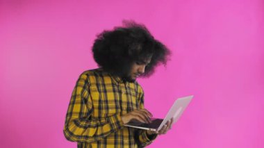 Mor arka planda dizüstü bilgisayar kullanan mutlu bir Afrikalı Amerikalı. Duyguların kavramı