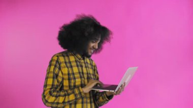 Mutlu Afrikalı Amerikalı adam dizüstü bilgisayar kullanıyor, gülümsüyor ve mor arka planda uzaklaşıyor. Duyguların kavramı