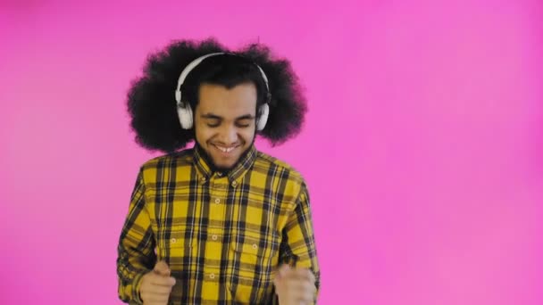 Positiv afroamerikansk man lyssnar musik i sina hörlurar på lila bakgrund. Begreppet känslor — Stockvideo