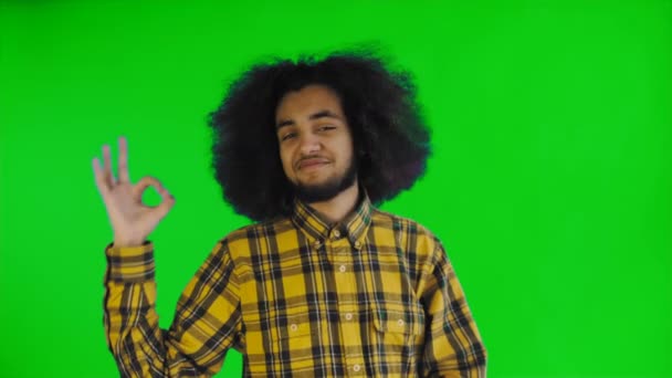 Sonriente chico afro-americano atractivo que muestra gesto aceptable mientras está de pie aislado sobre la pantalla verde o croma clave de fondo. Concepto de emociones — Vídeos de Stock