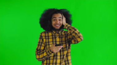 Genç mutlu Afrikalı iş adamı telefonu kullanıyor ve yeşil ekran ya da krom anahtar arka planda iyi haberler alıyor. Duyguların kavramı