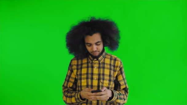 Молодой красивый африканский американец, использующий телефон на зеленом экране или хрома-ключевом фоне. Концепция эмоций — стоковое видео