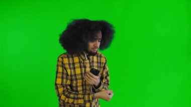 Pozitif Afro-Amerikan adam yeşil ekranda veya krom anahtar arka planda onun kulaklık müzik dinlemek için telefon kullanarak. Duygu kavramı