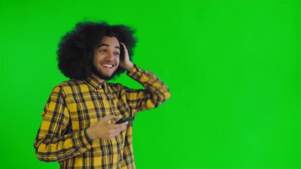 Gelukkige aantrekkelijke jonge Afro-Amerikaanse man met behulp van telefoon en het krijgen van goed nieuws op groen scherm of Chroma Key achtergrond. Concept van emoties — Stockvideo