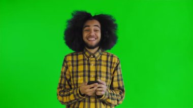 Genç mutlu Afrikalı iş adamı telefonu kullanıyor ve yeşil ekran ya da krom anahtar arka planda iyi haberler alıyor. Duyguların kavramı