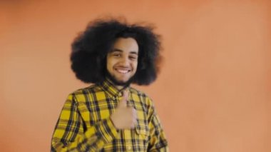 Genç mutlu Afro-Amerikan adam gülümserken portakal arka planda başparmak kaldırıyor. Duyguların kavramı