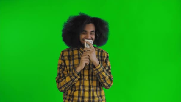Feliz joven afroamericano hombre sosteniendo el dinero en sus manos y mirando a la cámara en la pantalla verde o croma fondo clave . — Vídeo de stock