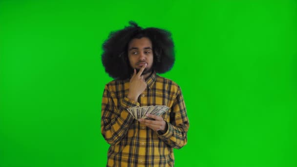 Hombre afroamericano sosteniendo el dinero en sus manos y pensando en algo en pantalla verde o croma clave fondo . — Vídeo de stock