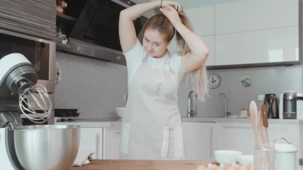 Belle femme de maison recueille ses cheveux dans une queue de cheval. Préparez-vous à cuire des gâteaux — Video