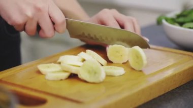 Kadın meyve püresi yapmak için soyulmuş muz kesti.