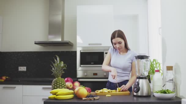 Kadın erkek arkadaşına meyve püresi yapmak için muz kesti. — Stok video