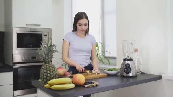 Frau schneidet eine geschälte Banane für den Smoothie — Stockvideo