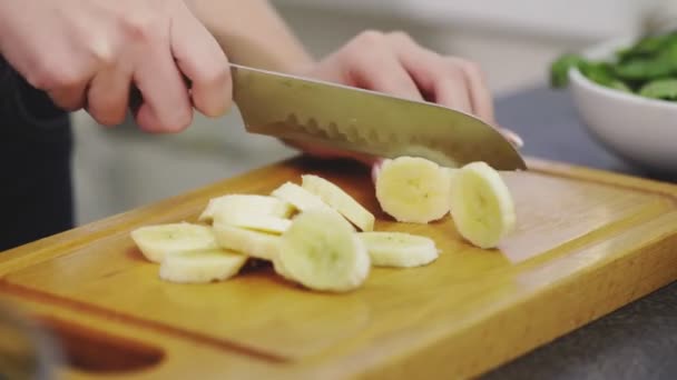 Κοντινό πλάνο του Woman κοπεί μια αποφλοιωμένη μπανάνα για να κάνει το smoothie — Αρχείο Βίντεο