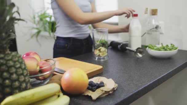 Frau macht Smoothie mit Milch im Mixer — Stockvideo