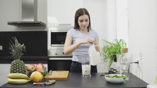 Bella giovane donna sta facendo il frullato di cocktail con latte nel frullatore — Video Stock