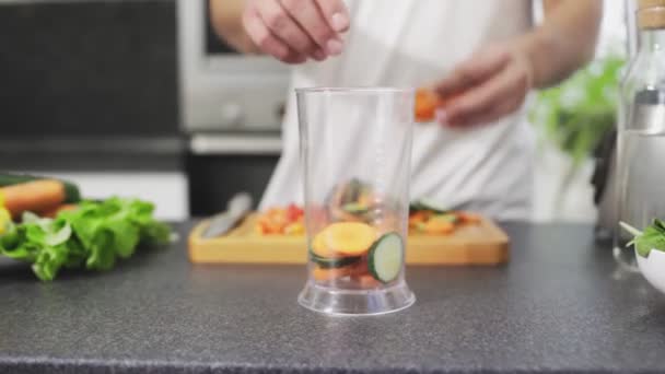 El hombre está poniendo verduras picadas a la licuadora — Vídeos de Stock