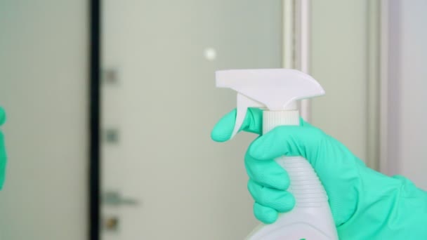 Жінка в рукавичках очищає дзеркало з ганчіркою та засобом для чищення в домашніх умовах — стокове відео