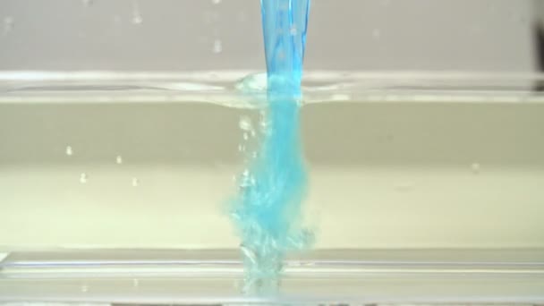 Blauwe vloeistof giet in transparant water — Stockvideo