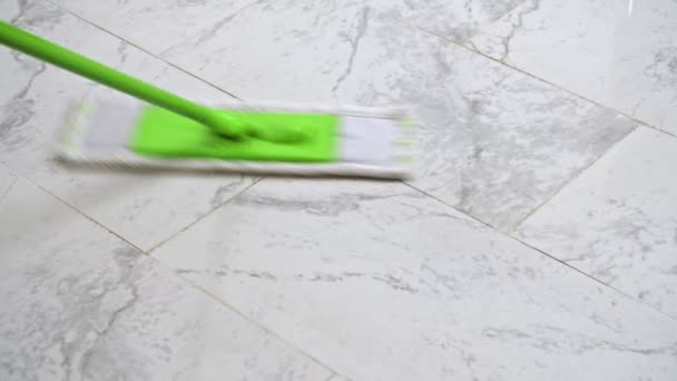 Žena čištění bílé podlahy se zeleným mikrovláknem mop