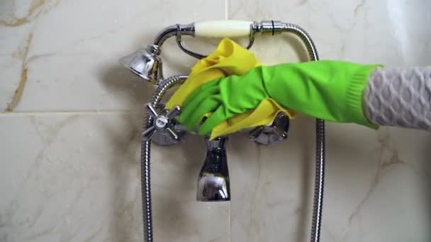 Hand in green glove is Cleaning bathroom faucet with yellow rag — Stock Video