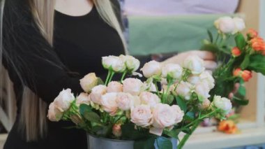 Çiçekçi buket yapmak için pembe bir gül alır.