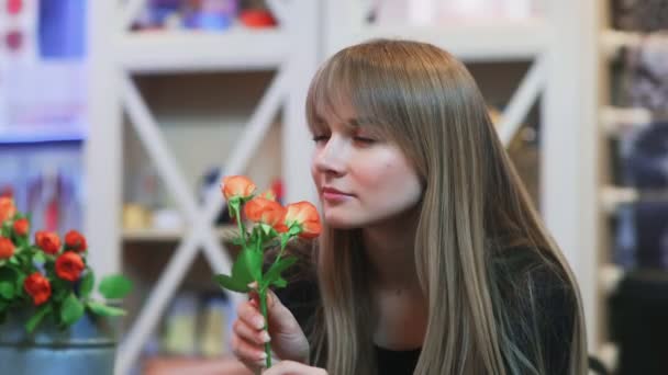 Une jeune femme sentant une fleur dans un magasin — Video