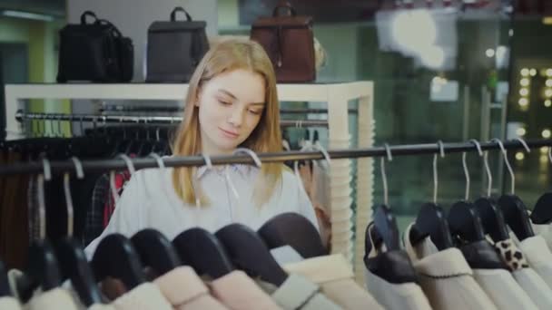 Νεαρή όμορφη γυναίκα επιλέξτε φόρεμα στο κατάστημα ρούχων — Αρχείο Βίντεο