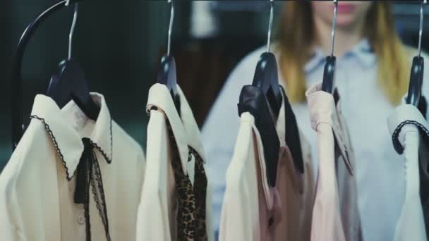 Dolly shot van Jonge mooie vrouw neemt alle blouses van hangers — Stockvideo