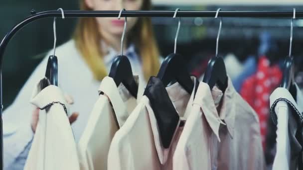 Mulher está tocando cabides com blusas no showroom — Vídeo de Stock