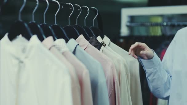Nahaufnahme einer Frau berührt Kleiderbügel mit Blusen im Showroom — Stockvideo
