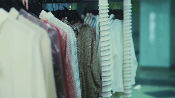 Una donna che fa shopping al centro commerciale. In piedi vicino a scaffali con vestiti che scelgono pullover. Raccogliendo camicia a scacchi — Video Stock