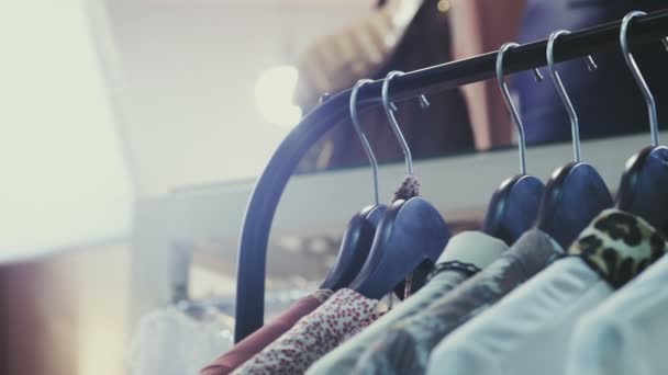 Dolly shot of clothes hangers close up auf dem verschwommenen Hintergrund — Stockvideo