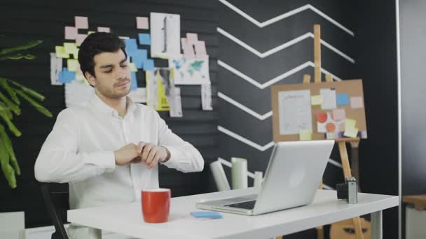 Νυσταγμένος νεαρός άντρας κάθεται στο γραφείο desktop με φορητό υπολογιστή — Αρχείο Βίντεο