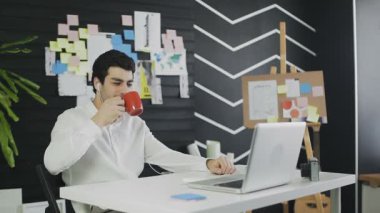 Kulaklıklı genç işadamı web kamerasıyla dizüstü bilgisayara bakıyor.