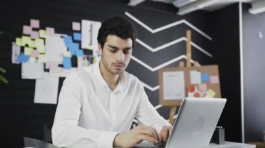 İşadamı kameraya baktıktan sonra dizüstü bilgisayar üzerinde çalışmaya başladı