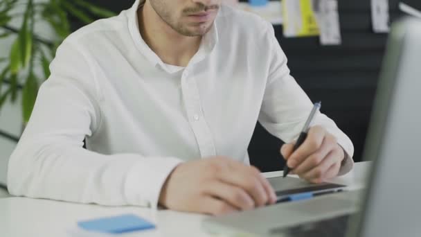 Concepteur masculin occasionnel utilisant une tablette graphique dans un bureau lumineux — Video