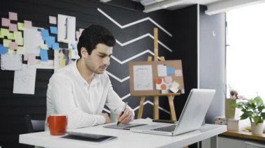 Gündelik erkek tasarımcı kahve içme ve grafik tablet kullanarak