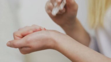 Güzel genç bir kadın ellerine patenli parfüm sürüyor.